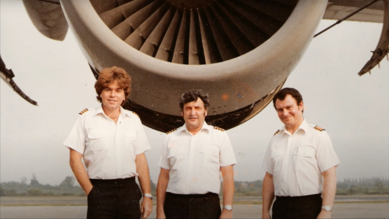 a group of men in uniform standing in front of a jet engine