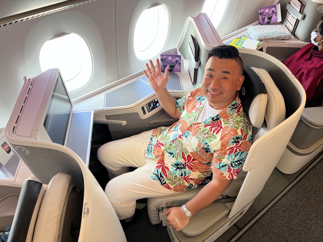 a man sitting in an airplane seat waving