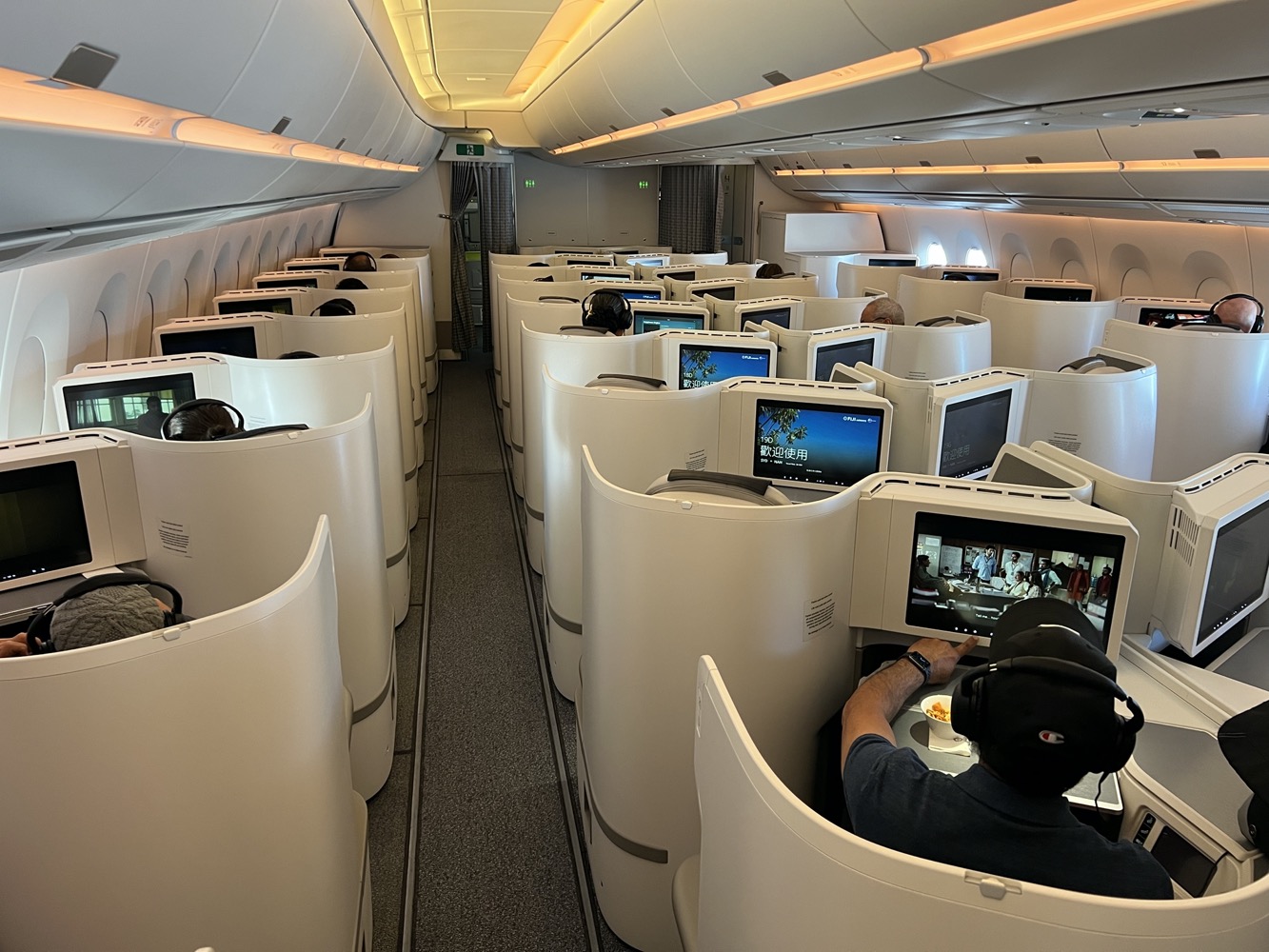 a group of people sitting in a row of white chairs with computers