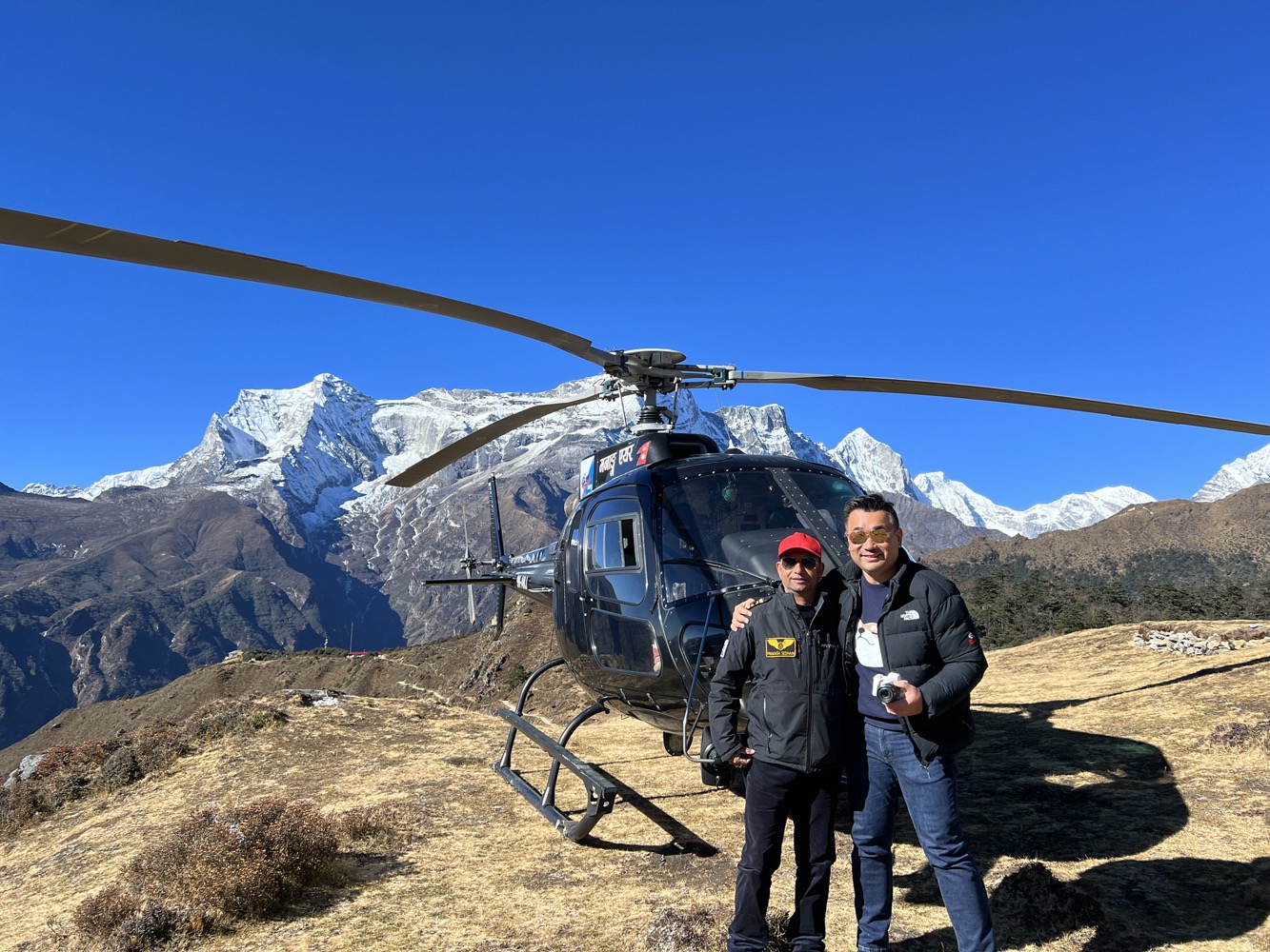two men standing in front of a helicopter