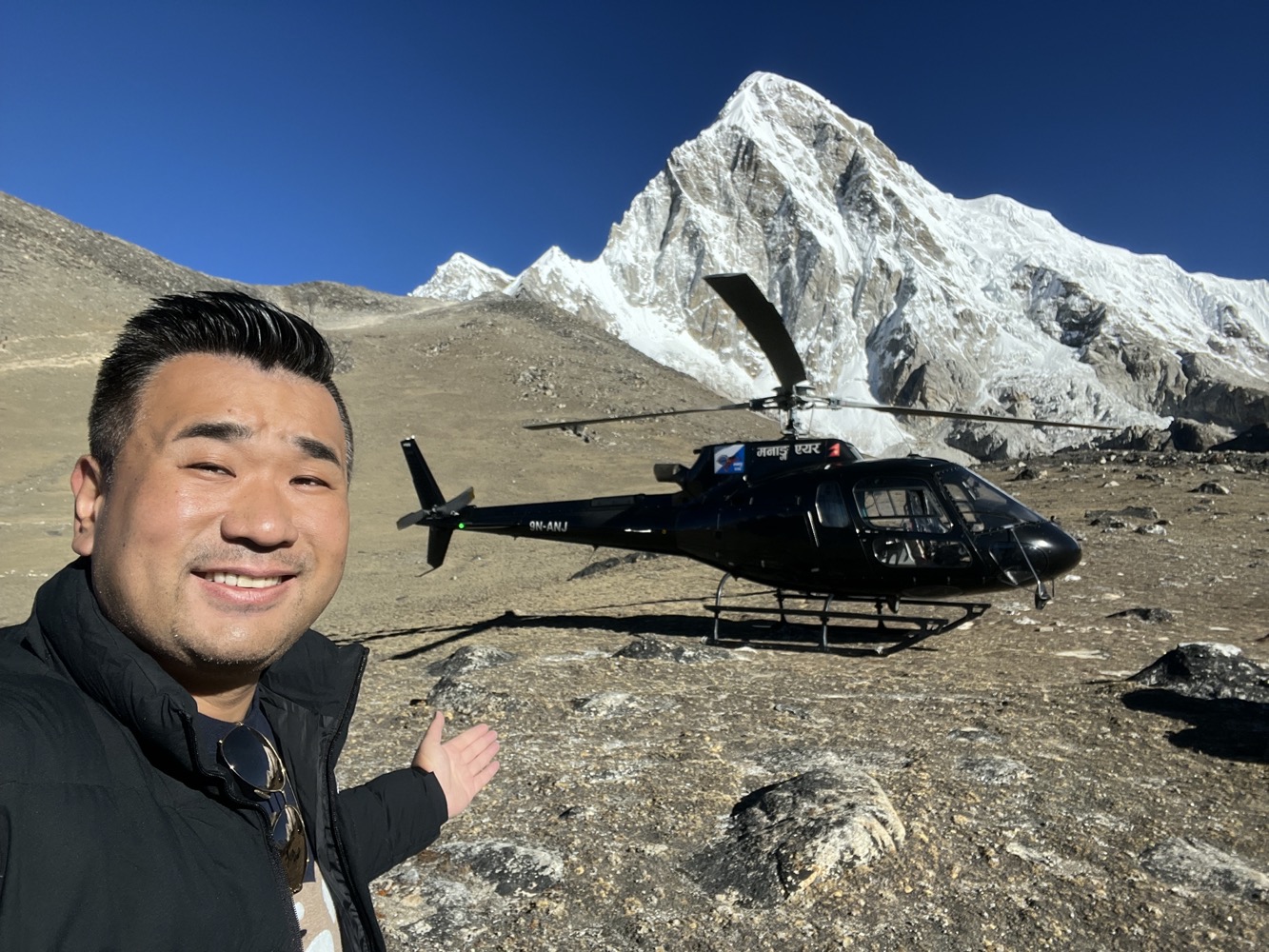 a man taking a selfie in front of a helicopter