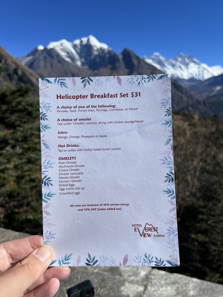 a hand holding a menu in front of mountains