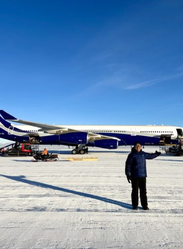 a man standing in the snow next to an airplane