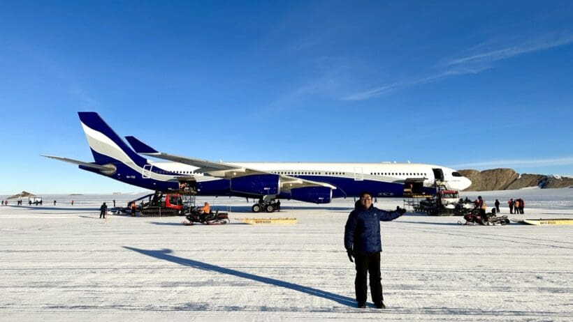 a man standing in the snow next to an airplane