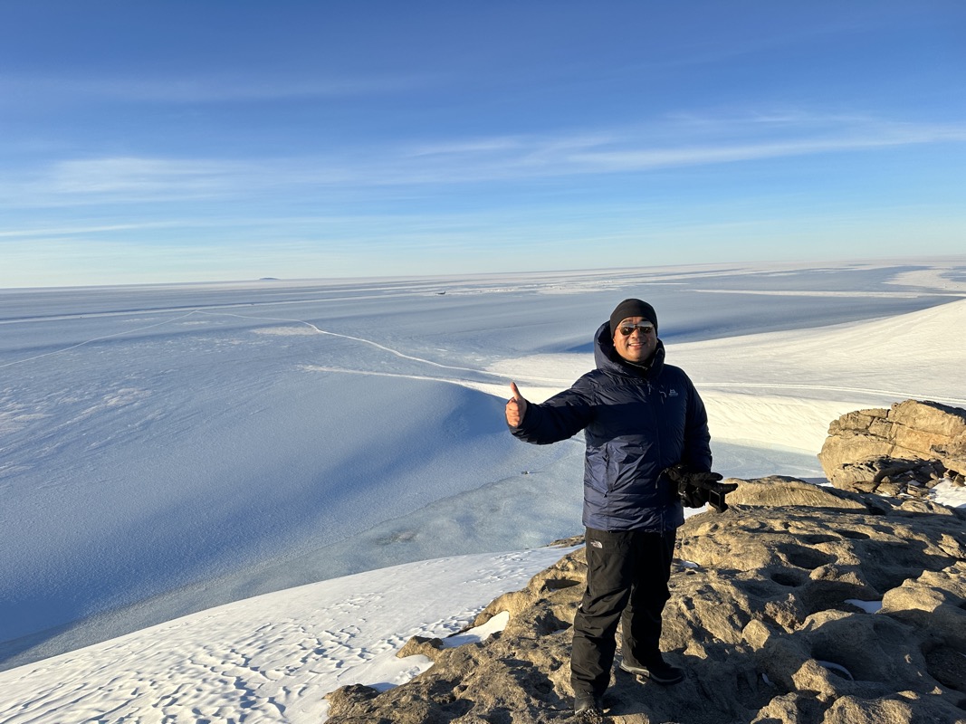 a man standing on a rock with a thumbs up in the air