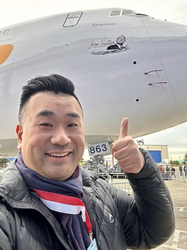 a man giving a thumbs up in front of a plane