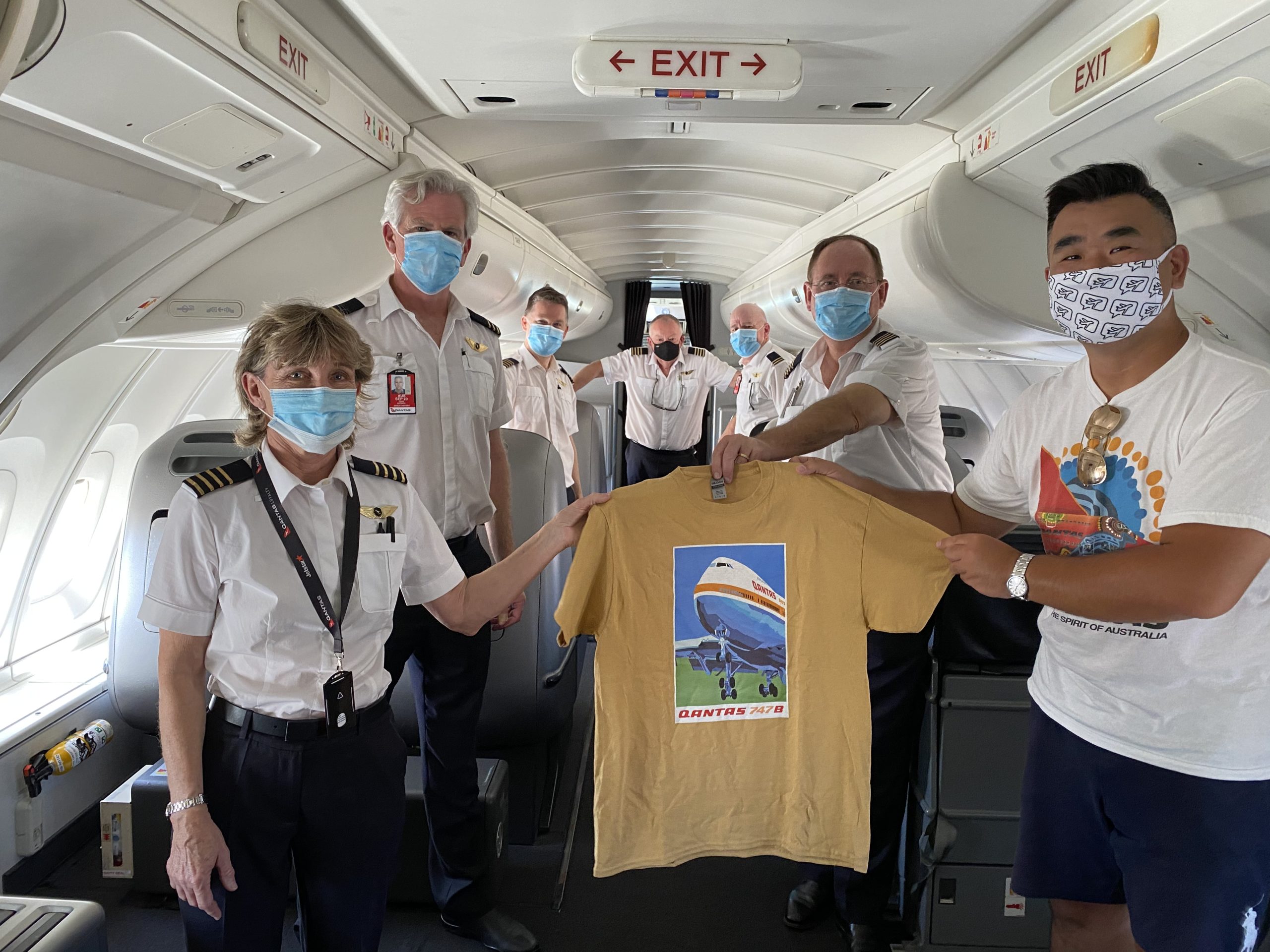 a group of people wearing face masks holding a shirt on an airplane