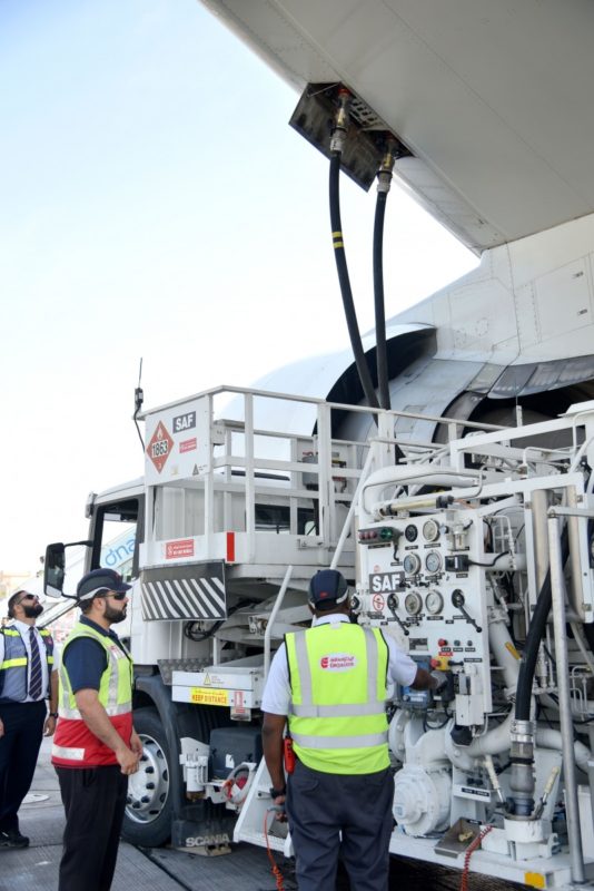 a group of men in safety vests standing next to a large white truck