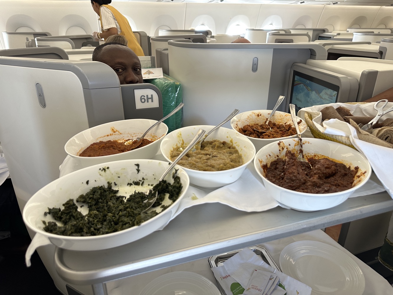 a man sitting in an airplane with food in bowls