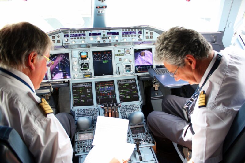 a man in uniform looking at a paper in a cockpit
