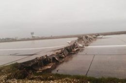 a broken road with a runway in the background