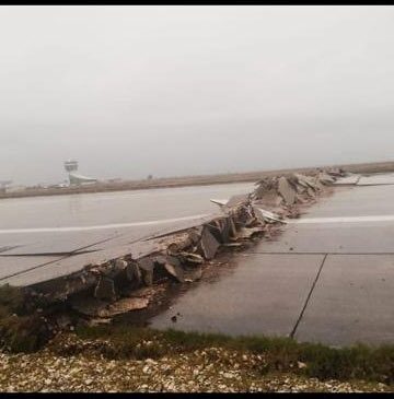 a broken road with a runway in the background