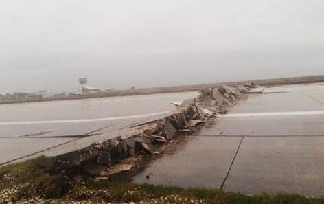 a broken road with a runway in the background