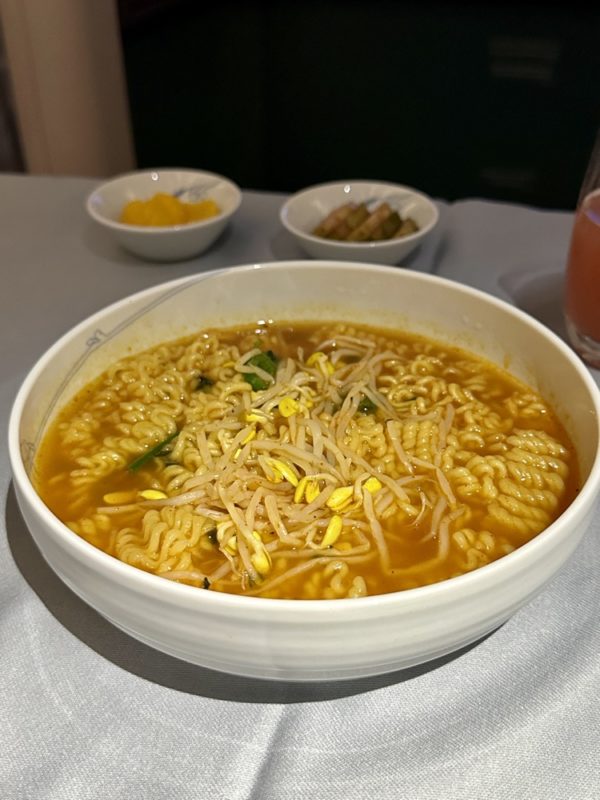 a bowl of soup with noodles and sprouts