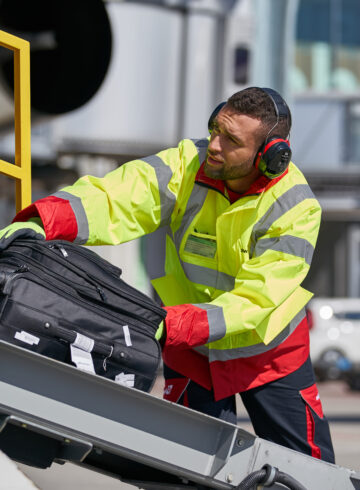 a man wearing headphones and a yellow jacket and holding a suitcase