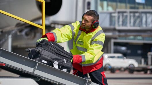 a man wearing headphones and a yellow jacket and holding a suitcase