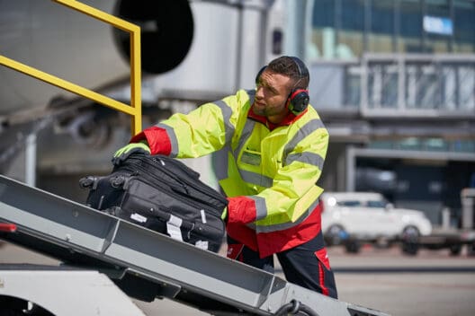 a man wearing headphones and a yellow jacket and holding a suitcase