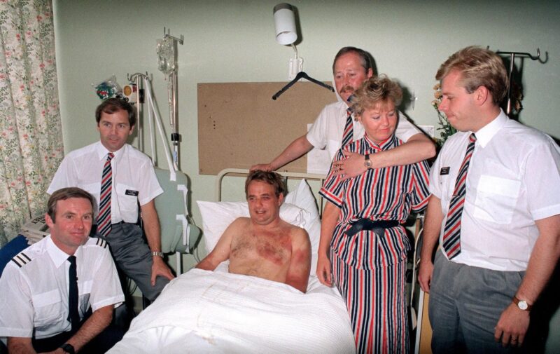 a group of people standing around a man in a hospital bed