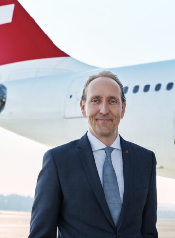 a man in a suit standing in front of a plane