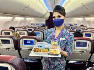 a woman wearing a face mask holding a tray of food