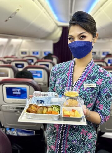 a woman wearing a face mask holding a tray of food