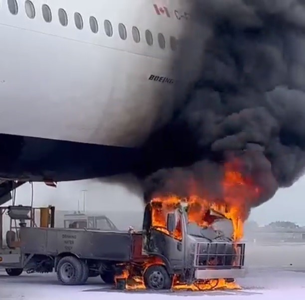 a truck on fire next to a plane