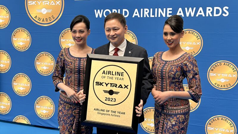 a man holding a framed sign with two women in dresses