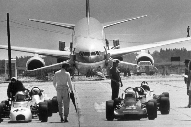 a plane and two men walking towards a race car