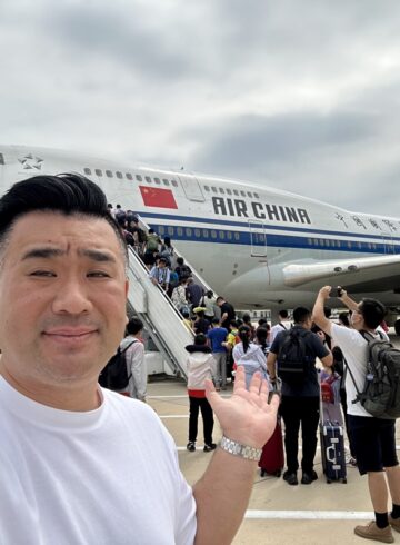 a man taking a selfie with a plane in the background