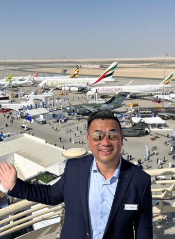 a man standing on a balcony with planes in the background