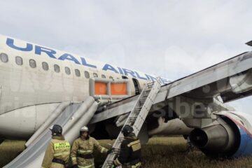 a group of people in fire suits standing next to an airplane