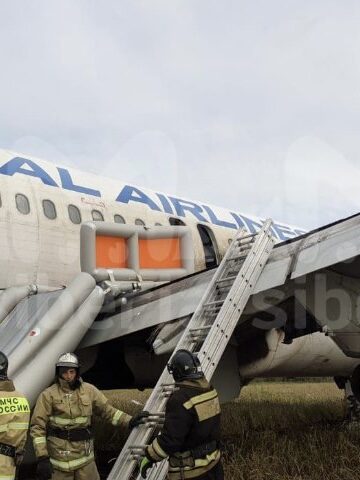 a group of people in fire suits standing next to an airplane