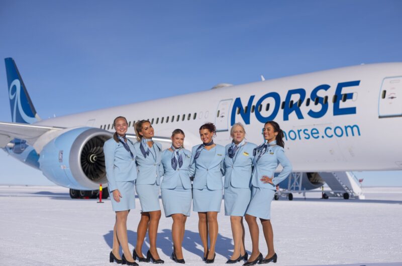 a group of women in blue uniforms standing in front of a plane