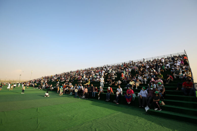 a large crowd of people sitting on a green bleachers
