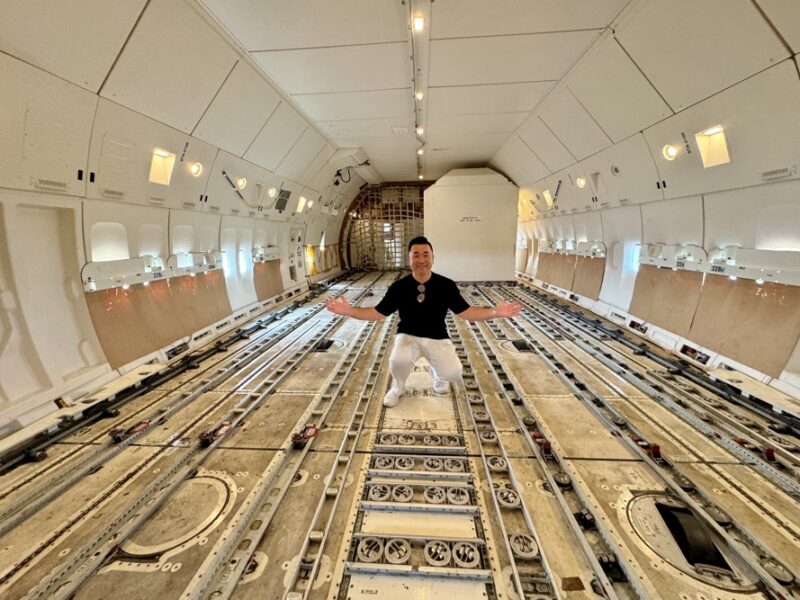 a man in a black shirt and white pants kneeling in a large white airplane