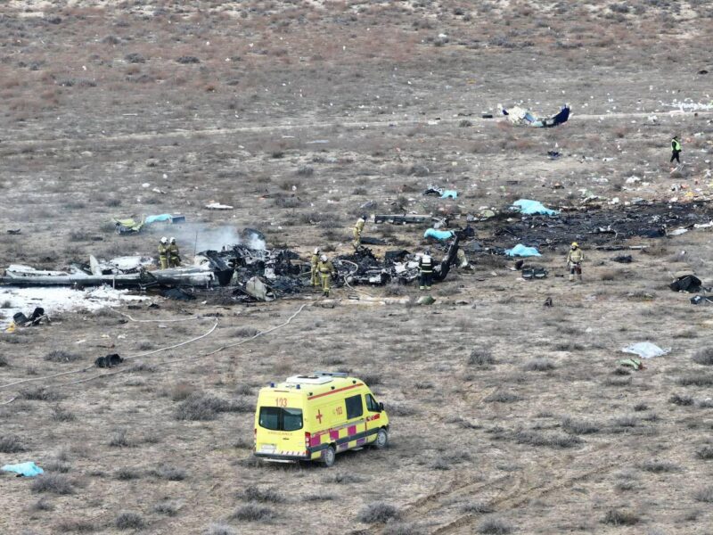 a group of people in a field with a crashed plane