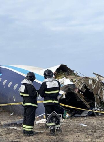 a group of people standing next to a crashed plane