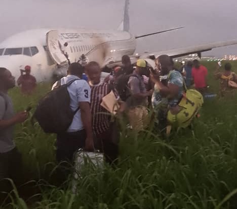 a group of people standing in a field with a plane