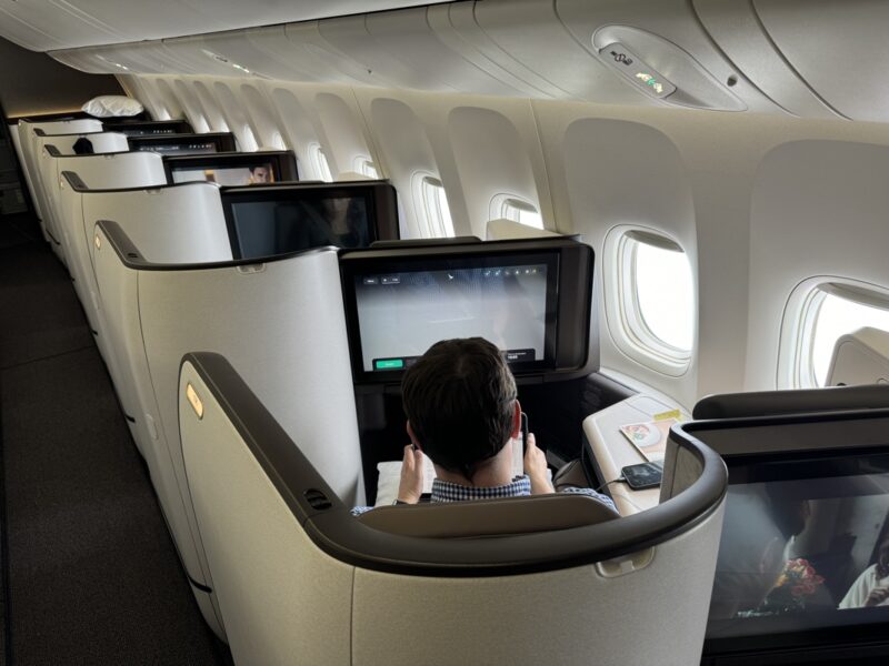 a man sitting in an airplane with a phone and monitors