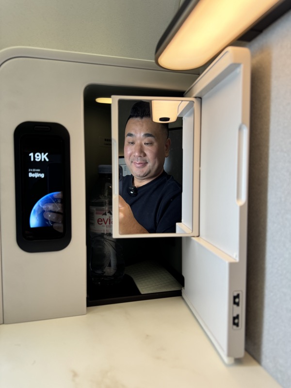 a man looking at a bottle in a small refrigerator