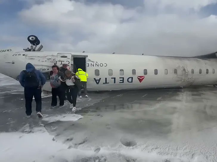 a group of people standing next to a plane that has been crashed