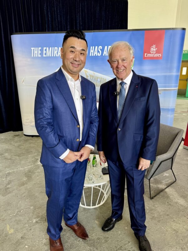 two men in suits standing in front of a banner