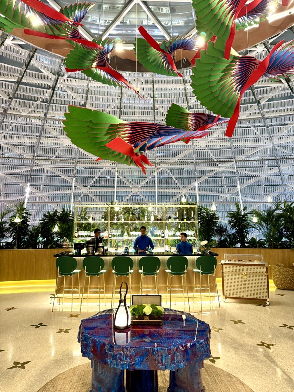 a bar with a colorful bird sculpture from the ceiling