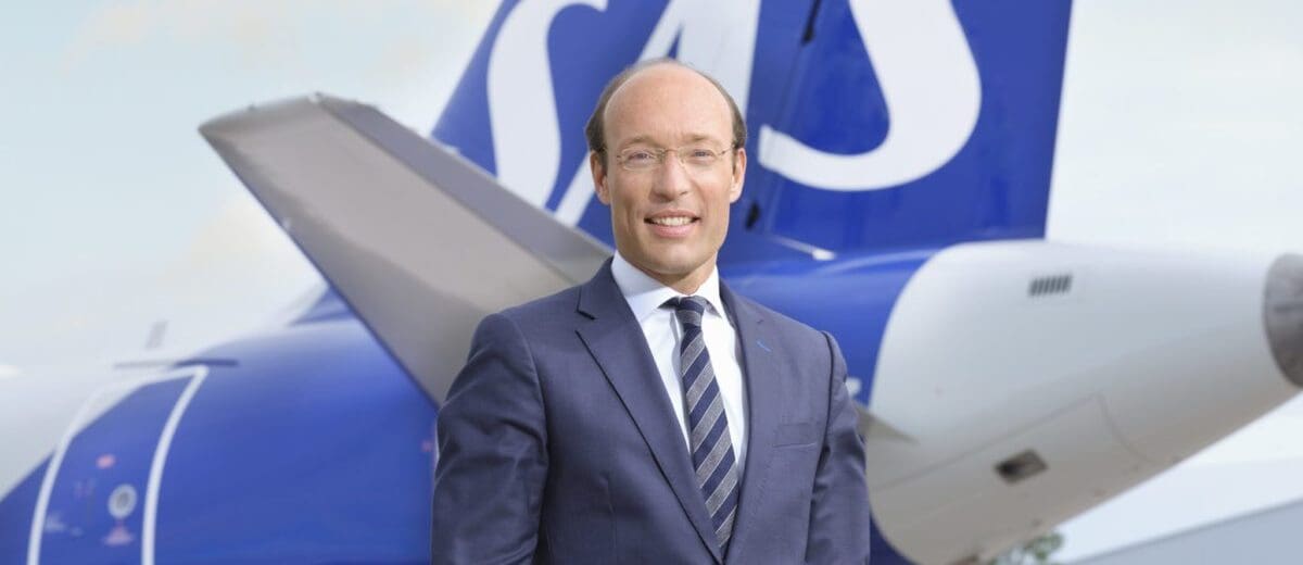a man in a suit standing in front of a plane