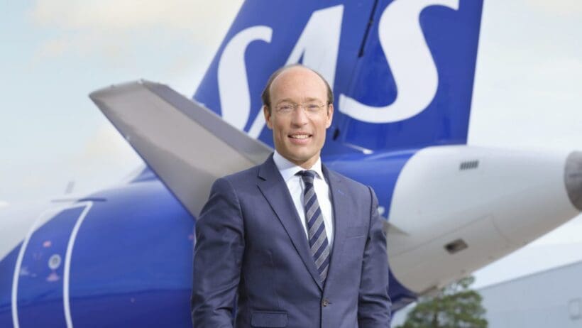 a man in a suit standing in front of a plane