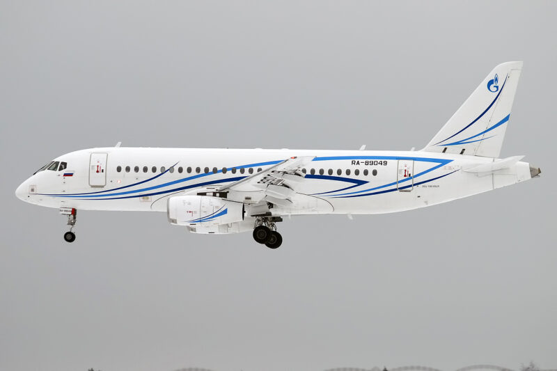 a white airplane with blue stripes flying in the sky