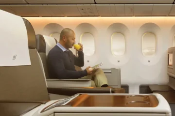 a man drinking a beverage while sitting on an airplane
