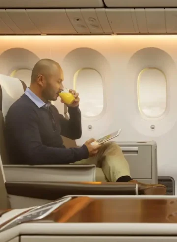 a man drinking a beverage while sitting on an airplane