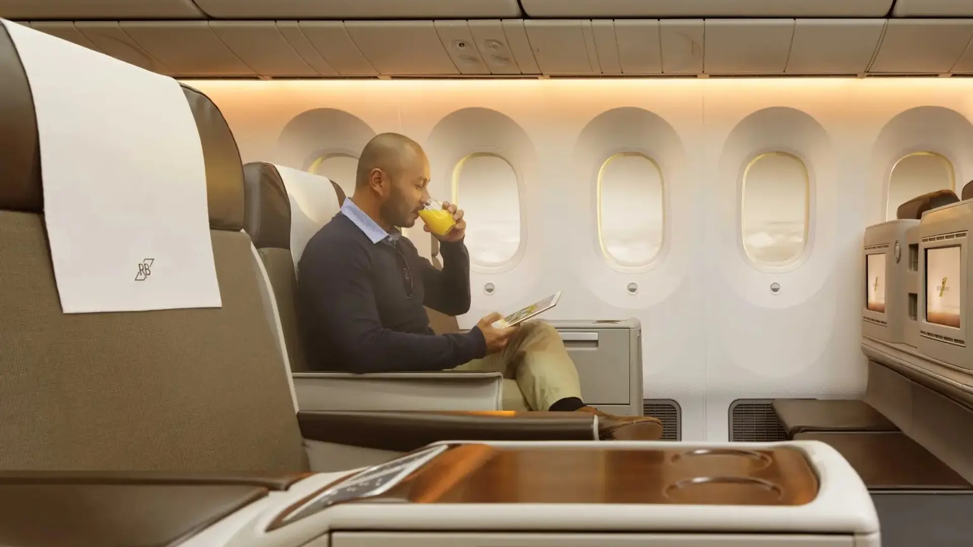 a man drinking a beverage while sitting on an airplane