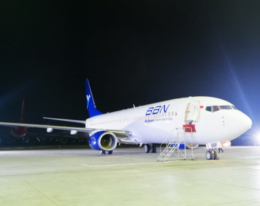 a white and blue airplane on a tarmac at night